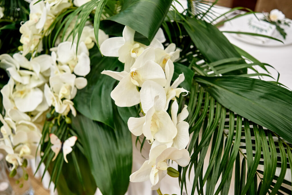 A summer floral arrangement featuring white orchids, Aspidistra and other lush tropical plants.